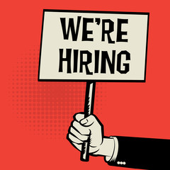 Hand holding poster, business concept with text We're Hiring