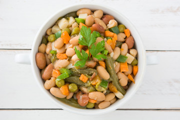 White beans with vegetables on white wooden table
