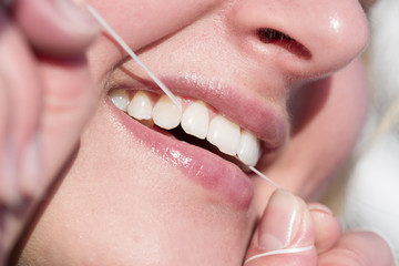 Mund einer Frau die Zahnseide benutzt