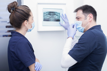 Dentist and assistant examining x-ray together at the dental clinic