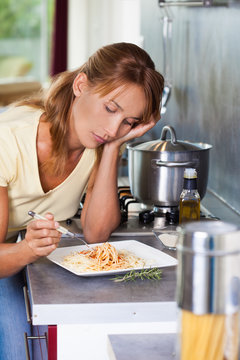 femme triste devant une assiette de pâtes