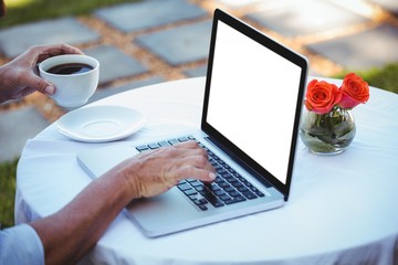 Fototapeta premium Close up of masculine hands using laptop and having coffee