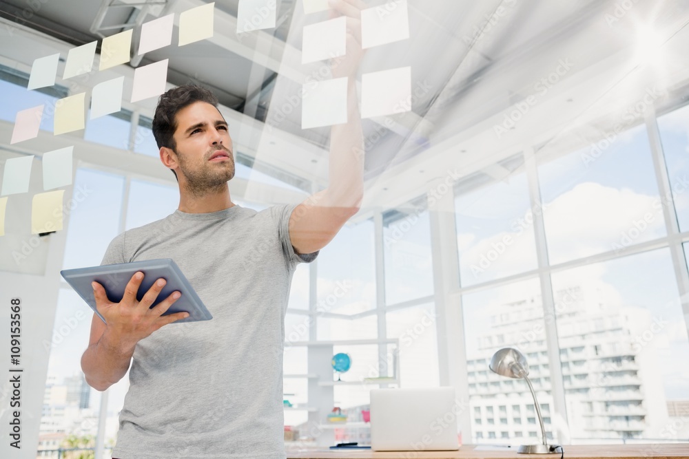 Poster man holding digital tablet and looking at sticky notes