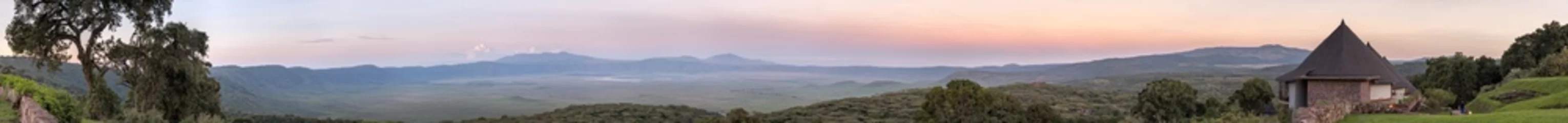 Schilderijen op glas Panoramic view of huge Ngorongoro caldera (extinct volcano crater) with lodge hotel bungalows against sunrise glow background. Great Rift Valley, Tanzania, East Africa.    © shujaa_777
