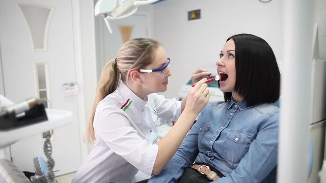 Young beautiful girl dentist treats teeth patient girl.
