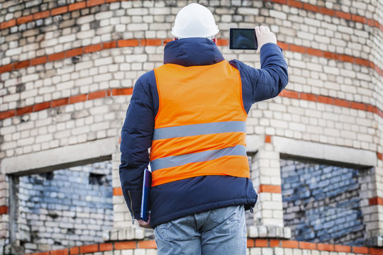 Civil engineer take pictures on tablet PC near building 
