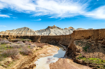 Wild scenery. Creek flowing under a canyon. Clay mountains in the background