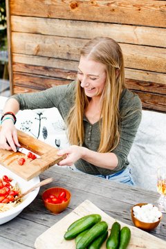 Woman scarping tomatoes into bowl from chopping board