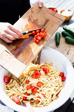 Woman scraping tomatoes into bowl with knife