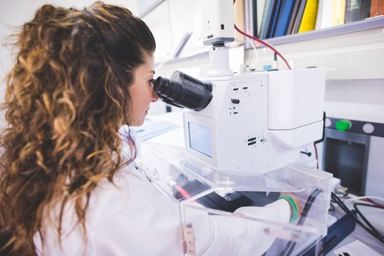 Female scientist using FTIR spectrophotometer, looking at thin film sample through the FTIR microscope