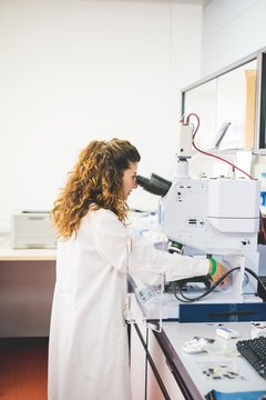 Female scientist using FTIR spectrophotometer, looking at thin film sample through the FTIR microscope