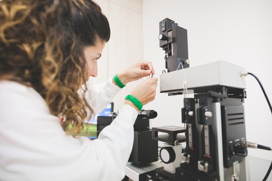 Female scientist looking at contact angle, preparing instrument for drop measurement on a specific substrate