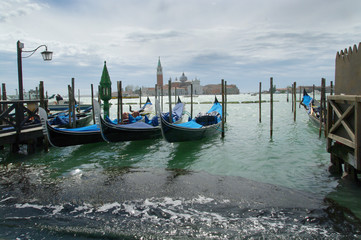 Fototapeta na wymiar Gondolas moored by Saint Mark square with San Giorgio di Maggiore church in the background - Venice, Venezia, Italy, Europe 
