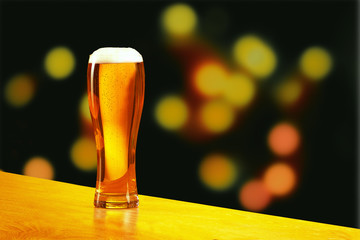 A glass of light beer on a background of blurred lights