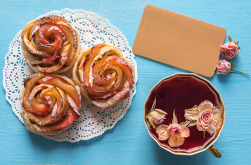 Homemade apple cake roses and herbal tea on wooden background. Top view
