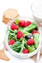 Green  salad with arugula and berries and pine nuts on white tab