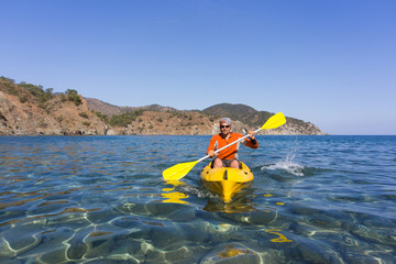 Men travel by canoe on the sea in the summer.