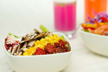 Closeup delicate fresh presentation of salad in white bowl with colourful vegetables such as mushrooms, corn and sundried omatoes