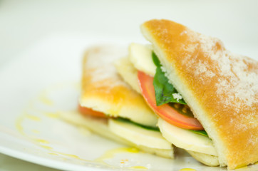 Delicious cheese, albahaca basil and tomato ciabatta sandwich on white plate