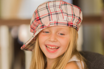 Portrait of a smiling girl in a checkered cap with long hair
