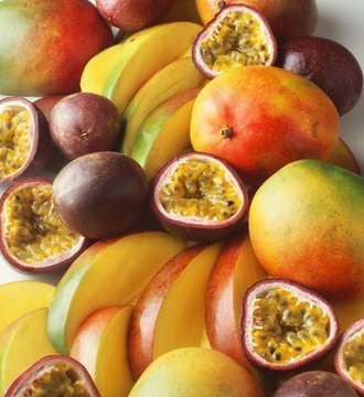 Stack of tropical fruit with mangoes and passion fruit, sliced and whole