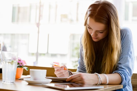 Young woman in cafe looking down writing