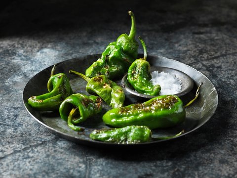 Green padron peppers in metal dish with bowl of sea salt