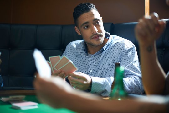 Male friends playing card game at pub card table