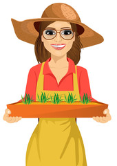 Young farmer woman with glasses holding a box of fresh green seedlings plants