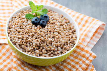 Buckwheat porridge in a bowl with mint leaves and blueberries.