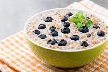 Buckwheat porridge in a bowl with mint leaves and blueberries.