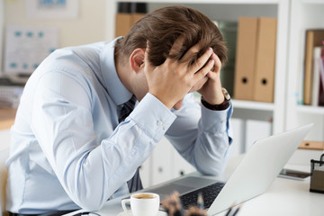 Tired business man at workplace in office holding his head in ha