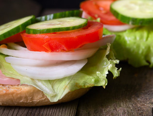 Sandwich with salad and other vegetables on old gray boards