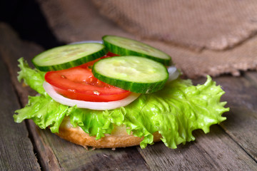 Sandwich with salad and other vegetables on old gray boards