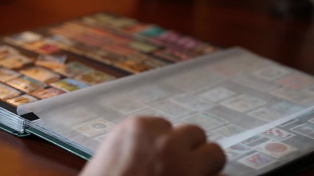 Philatelist looks stamps in an album through a magnifying glass
