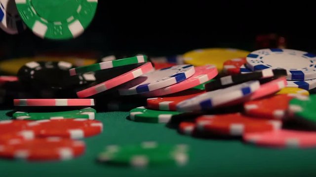 Winning jackpot in casino, many poker chips falling on green table in slowmotion