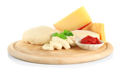 Fresh dough and other different ingredients for pizza on cutting board isolated on white