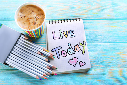 Fototapeta Cup of coffee with note LIVE TODAY and crayons on wooden background