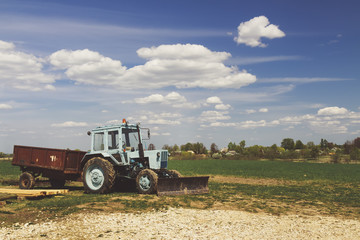 Obraz premium Tractor in the field with blue sky and clouds