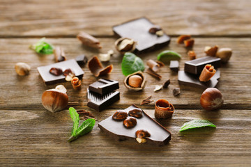 Broken black chocolate with hazelnuts and fresh mint on wooden table