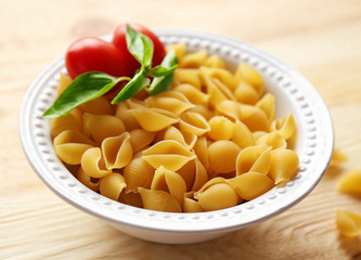 Dry conchiglie pasta in white plate on wooden table