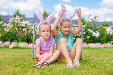 Two adorable little sisters wearing bunny ears on Easter day outdoors