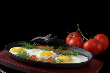 Scrambled eggs with tomatoes and whole tomatoes, on a black background