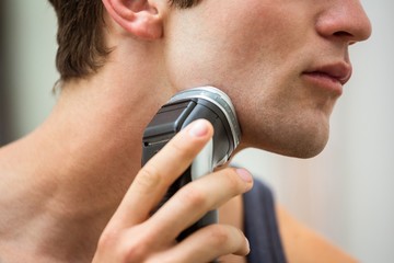Mid-section of man shaving with trimmer