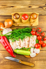 Sliced fresh pork lard, fresh produce, greens, vegetables on the wooden board and knife on table, top view.