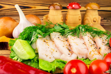 Sliced fresh pork lard, fresh produce, greens, vegetables on the wooden board, close-up, selective focus.