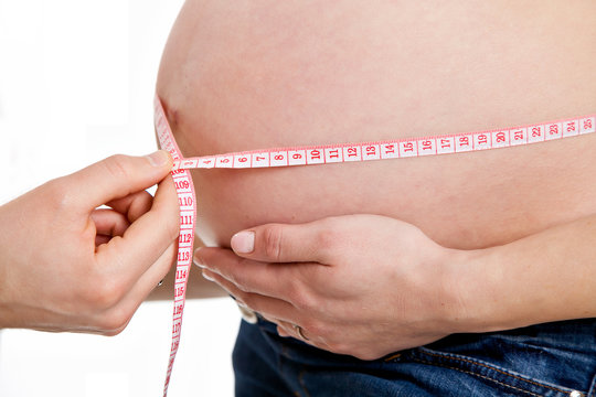 pregnant woman's belly with a measuring tape