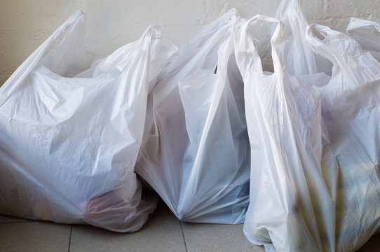 Full frame view of full plastic shopping bags on tiled floor