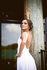 Fototapeta premium Beautiful sexy brunette bride in white dress walking up stairs