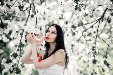 Portrait of young dark-haired woman in the flowered garden in th